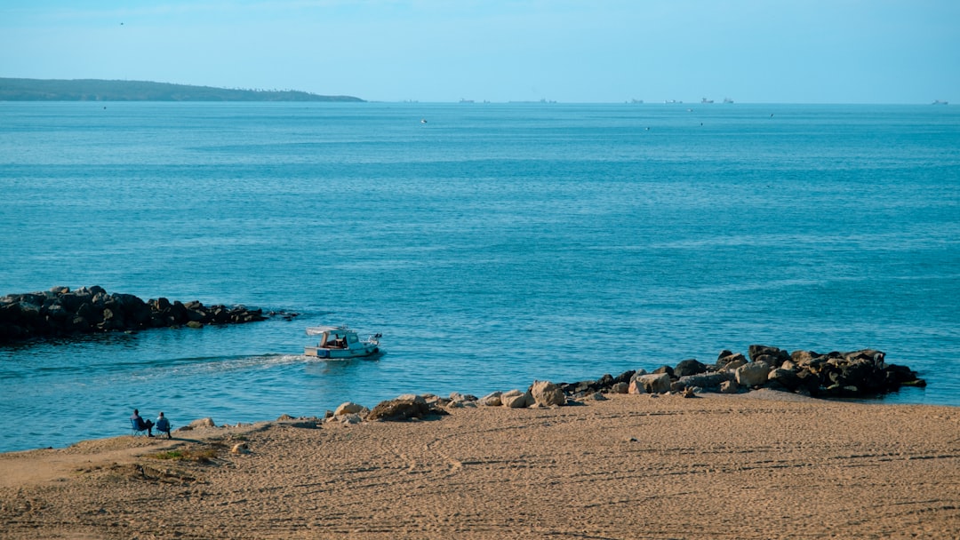 Motorboat leaving a rocky harbor into calm blue water